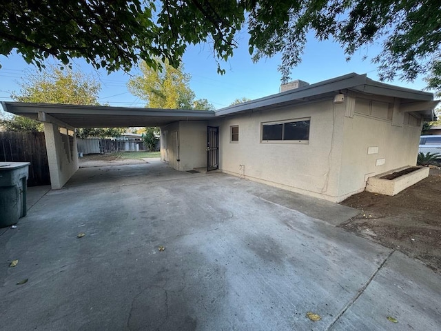 view of front of home with concrete driveway, fence, and a carport