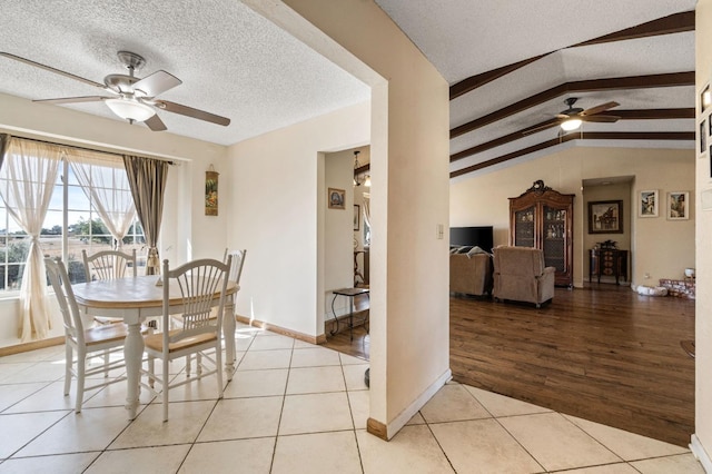 dining space with light tile patterned floors, lofted ceiling with beams, a ceiling fan, and a textured ceiling