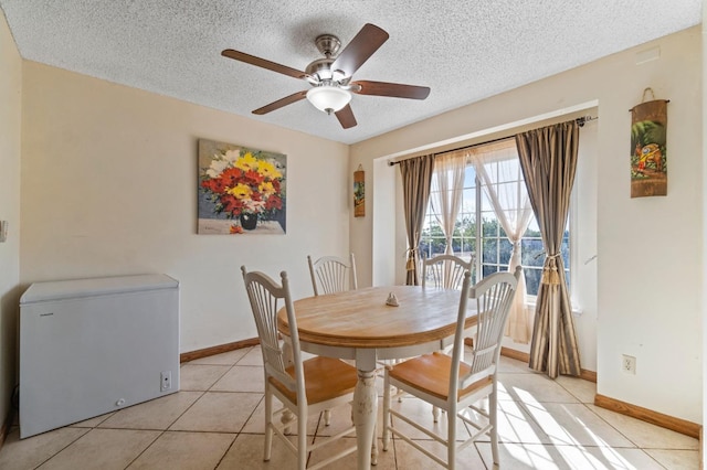 dining room with a textured ceiling, ceiling fan, light tile patterned flooring, and baseboards