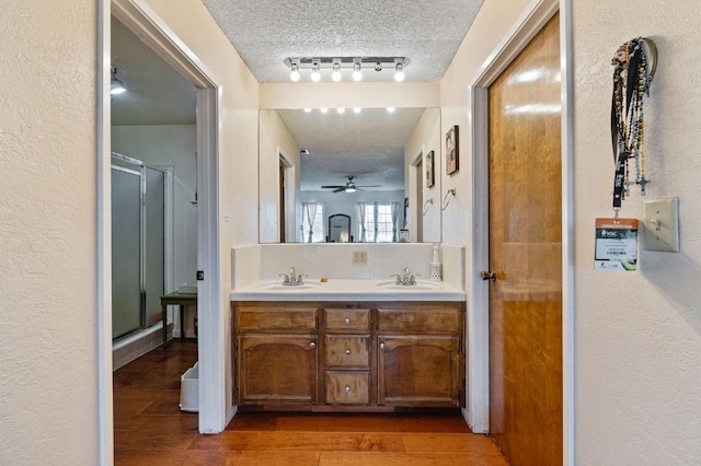 full bath with a sink, a textured ceiling, and wood finished floors