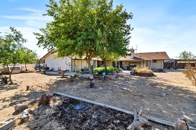 rear view of house featuring board and batten siding, a patio, and fence