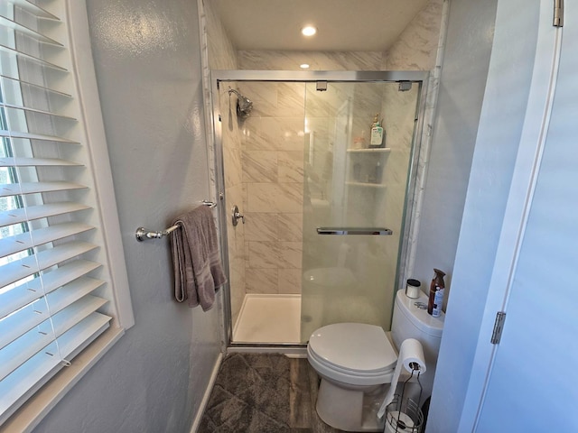 bathroom with a shower with door and toilet