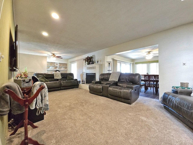 carpeted living room featuring ceiling fan and a brick fireplace