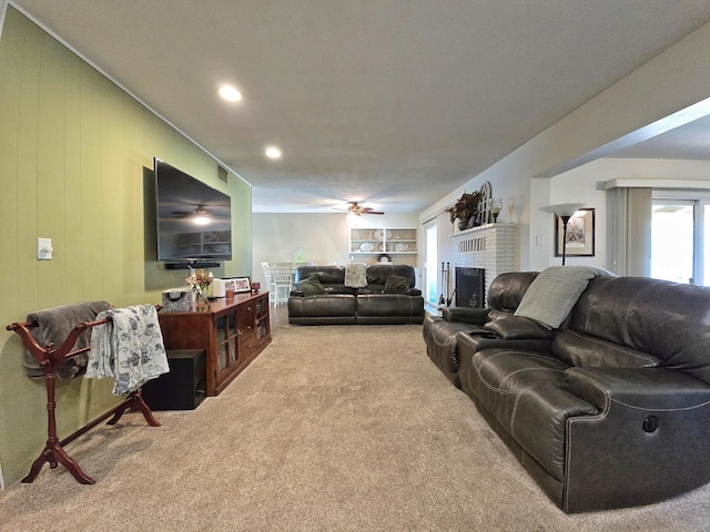 carpeted living room featuring a fireplace, wooden walls, and ceiling fan