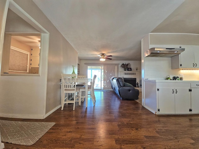 unfurnished dining area with a brick fireplace, dark hardwood / wood-style floors, and ceiling fan