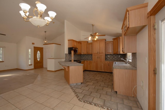 kitchen featuring tasteful backsplash, a kitchen island, a kitchen bar, ceiling fan with notable chandelier, and sink