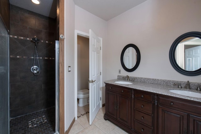 bathroom featuring vanity, a tile shower, toilet, and tile patterned flooring