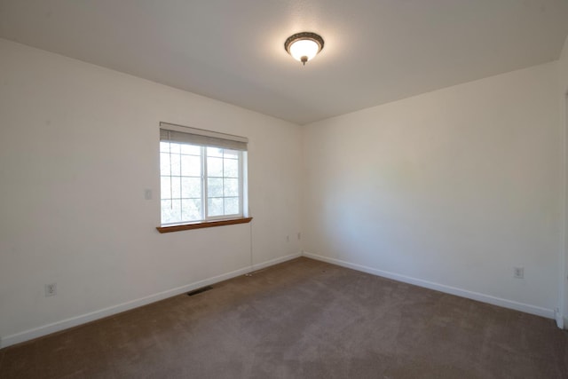 unfurnished room featuring dark colored carpet