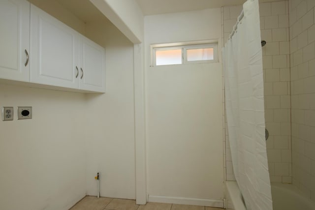 laundry area with electric dryer hookup and light tile patterned floors