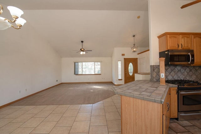 kitchen featuring tasteful backsplash, appliances with stainless steel finishes, kitchen peninsula, pendant lighting, and tile counters