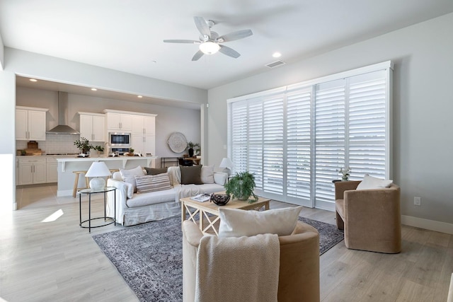 living room featuring ceiling fan and light hardwood / wood-style floors