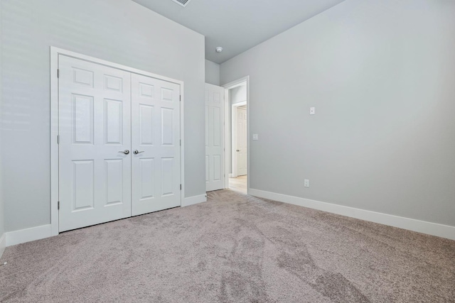 unfurnished bedroom featuring light carpet and a closet