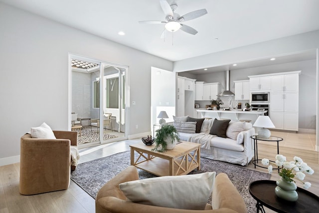 living room featuring sink, light hardwood / wood-style flooring, and ceiling fan