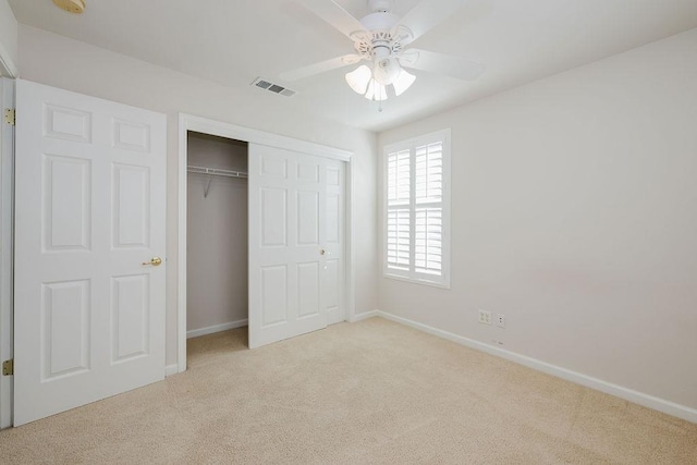 unfurnished bedroom featuring ceiling fan, light colored carpet, and a closet