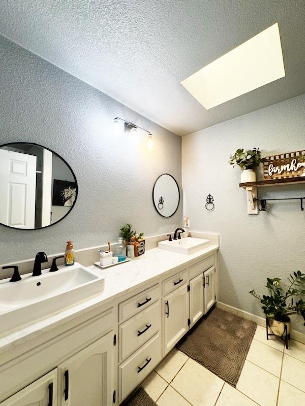 bathroom featuring vanity, a textured ceiling, tile patterned floors, and a skylight