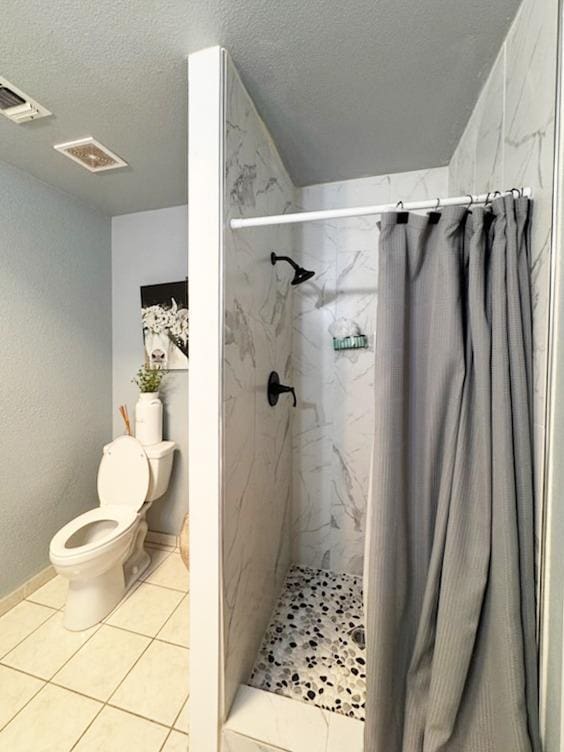 bathroom with toilet, a textured ceiling, and a shower with shower curtain