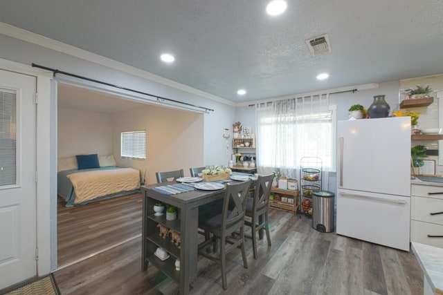 dining area featuring ornamental molding, dark hardwood / wood-style floors, and a textured ceiling