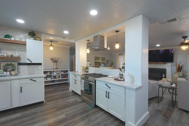 kitchen featuring hanging light fixtures, wall chimney exhaust hood, stainless steel range, white cabinets, and dark wood-type flooring