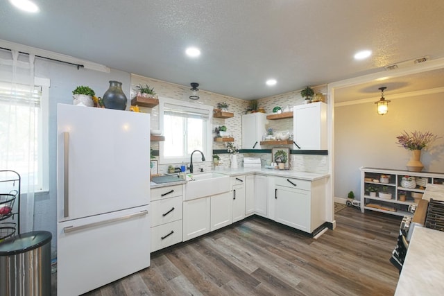 kitchen with hanging light fixtures, dark hardwood / wood-style flooring, white cabinetry, crown molding, and white fridge