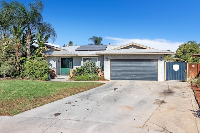 ranch-style home with a front yard, a garage, and solar panels