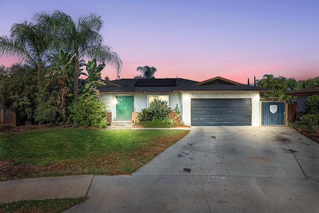 single story home featuring solar panels, a lawn, and a garage