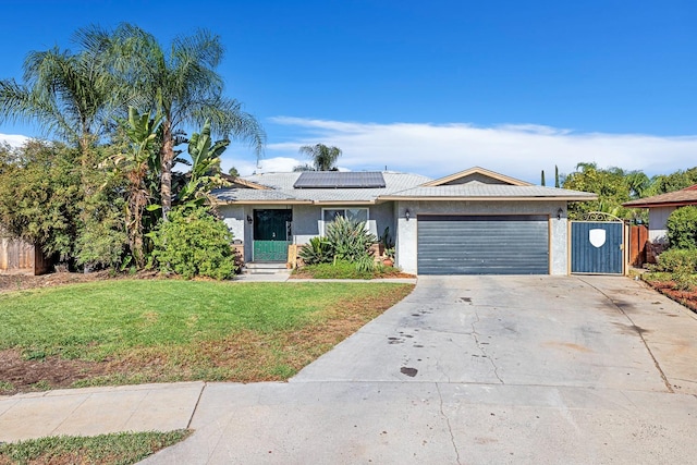 ranch-style home with solar panels, a front lawn, and a garage