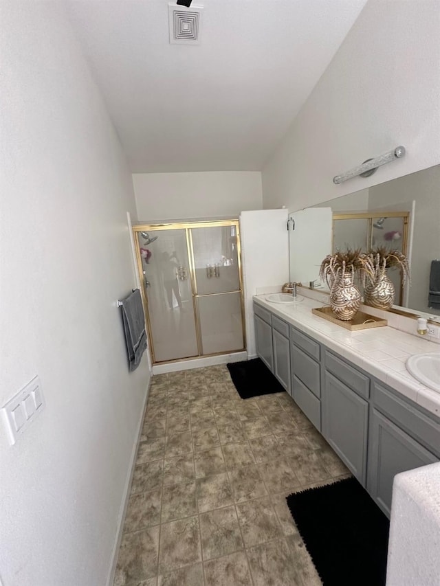 bathroom with a shower with door, lofted ceiling, and vanity