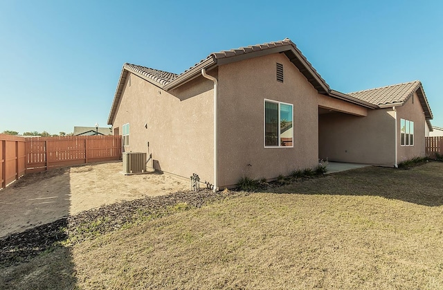 rear view of house featuring a patio, central AC, and a yard