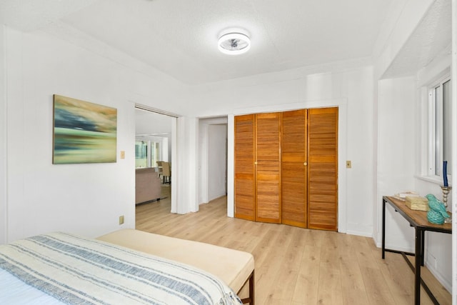 bedroom with a closet, a textured ceiling, and light wood-type flooring