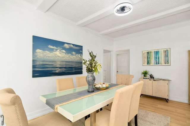 dining area with beam ceiling, hardwood / wood-style flooring, and a textured ceiling