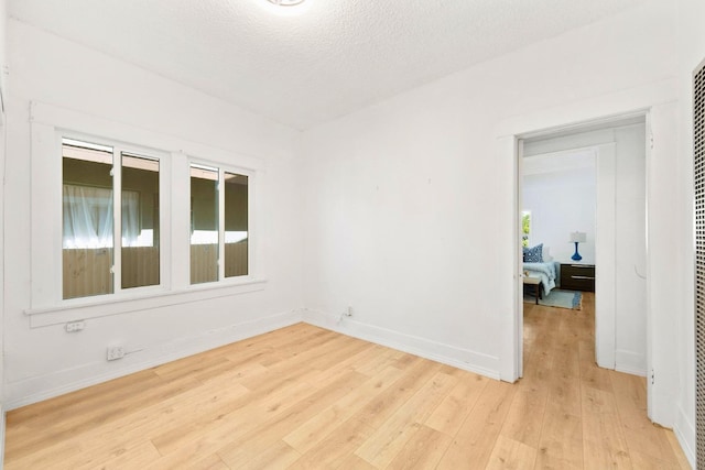 unfurnished room with light hardwood / wood-style floors and a textured ceiling