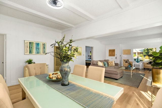 dining room with beam ceiling, a textured ceiling, and light hardwood / wood-style floors