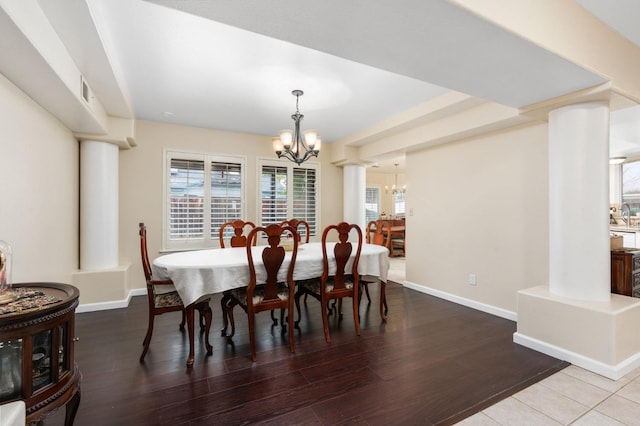 dining room with ornate columns, wood-type flooring, and an inviting chandelier