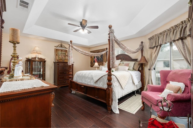 bedroom with a raised ceiling, ceiling fan, and dark hardwood / wood-style floors