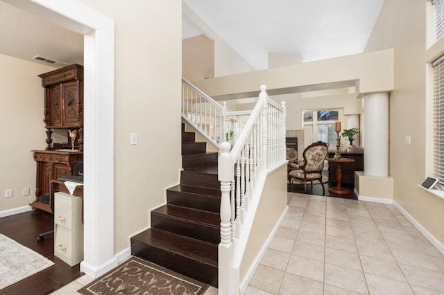 stairway featuring a fireplace, wood-type flooring, and vaulted ceiling