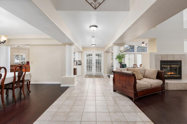 foyer featuring ceiling fan with notable chandelier, light hardwood / wood-style floors, a fireplace, and decorative columns