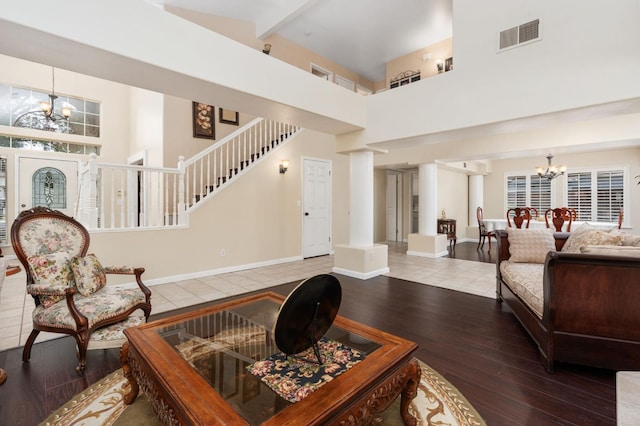 living room featuring hardwood / wood-style floors, beamed ceiling, a high ceiling, and a chandelier