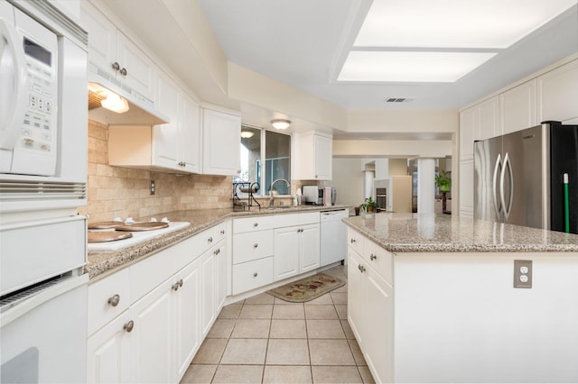 kitchen featuring tasteful backsplash, white appliances, sink, white cabinets, and a center island