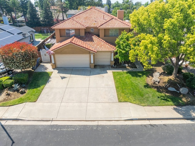 mediterranean / spanish home with a garage and a front lawn