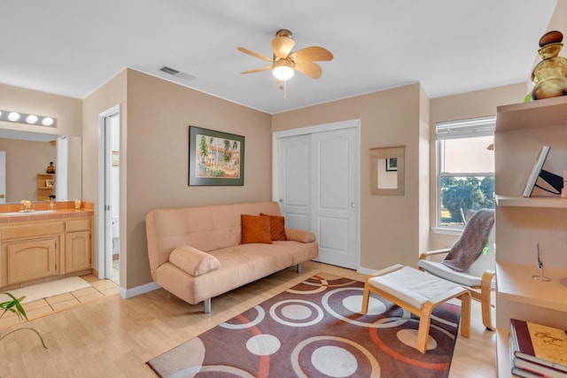 living room with sink, light wood-type flooring, and ceiling fan