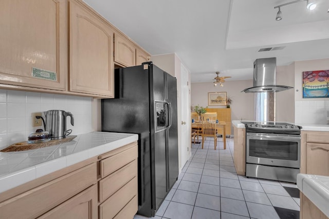 kitchen featuring island range hood, tile countertops, black fridge with ice dispenser, light brown cabinetry, and electric stove