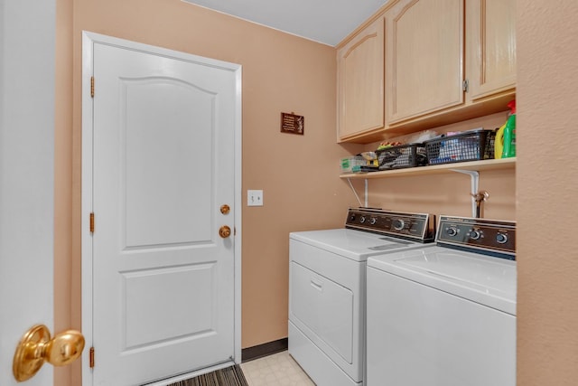 clothes washing area with washing machine and dryer and cabinets