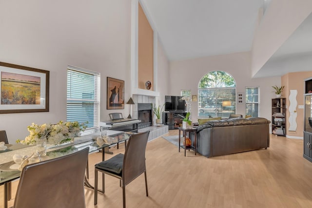 living room featuring light hardwood / wood-style flooring, high vaulted ceiling, and a fireplace