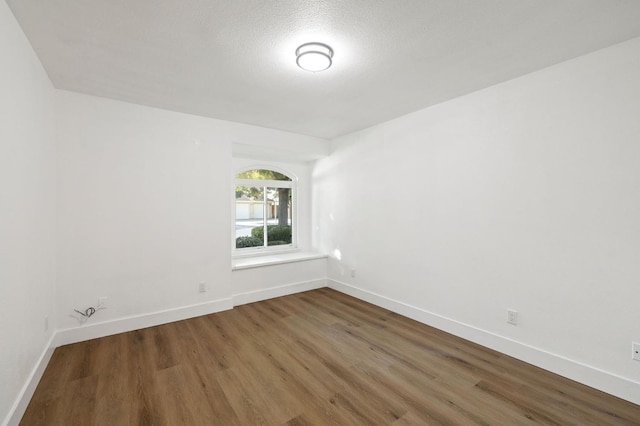 empty room featuring a textured ceiling and dark wood-type flooring