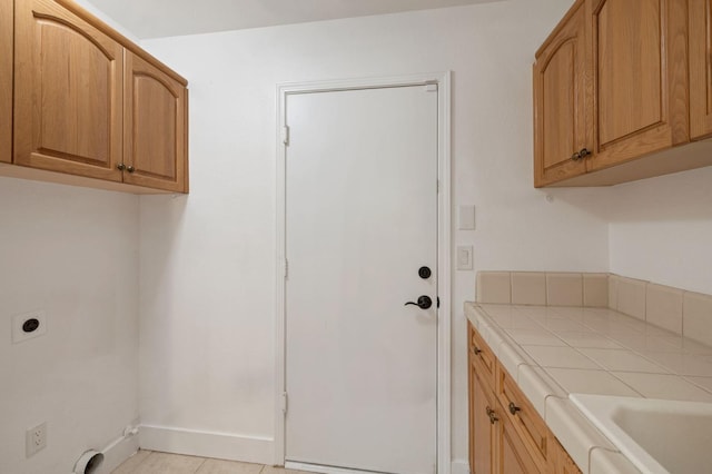 laundry area with hookup for an electric dryer, light tile patterned floors, and cabinets