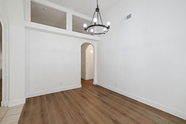 unfurnished dining area with a notable chandelier, ornamental molding, and hardwood / wood-style flooring