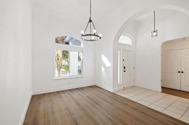 entrance foyer featuring a notable chandelier, high vaulted ceiling, and light wood-type flooring