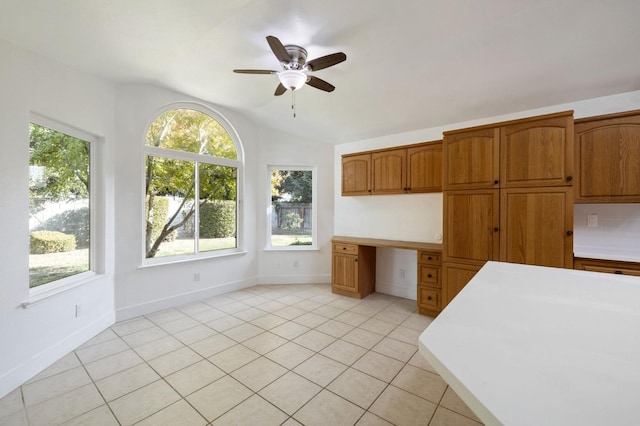 kitchen with built in desk, ceiling fan, lofted ceiling, and light tile patterned flooring