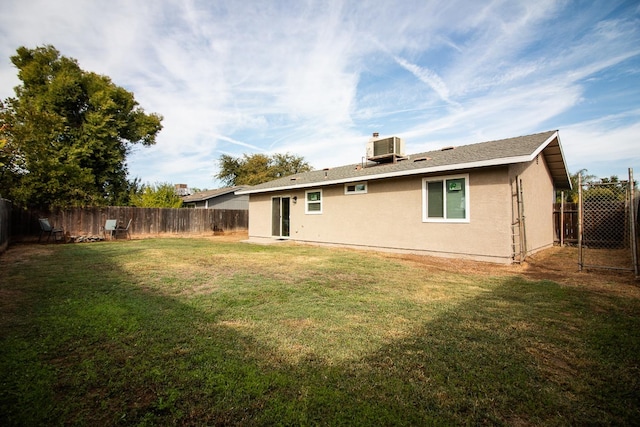 rear view of house featuring cooling unit and a lawn