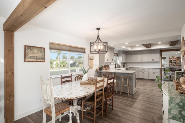 dining space featuring dark hardwood / wood-style floors, beam ceiling, sink, and a chandelier